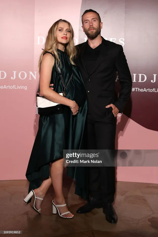 Teresa Palmer standing with a companion in a dark dress.