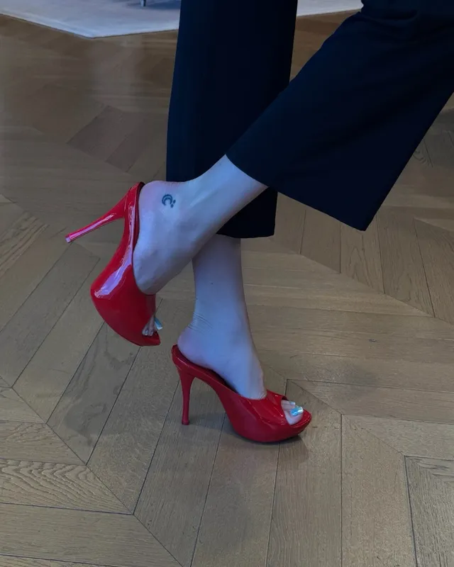 Bella Thorne wearing red heels beneath dark trousers.