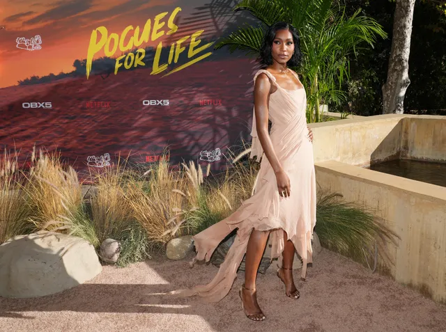 Carlacia Grant posing in a pale dress and heels at an Outer Banks event.