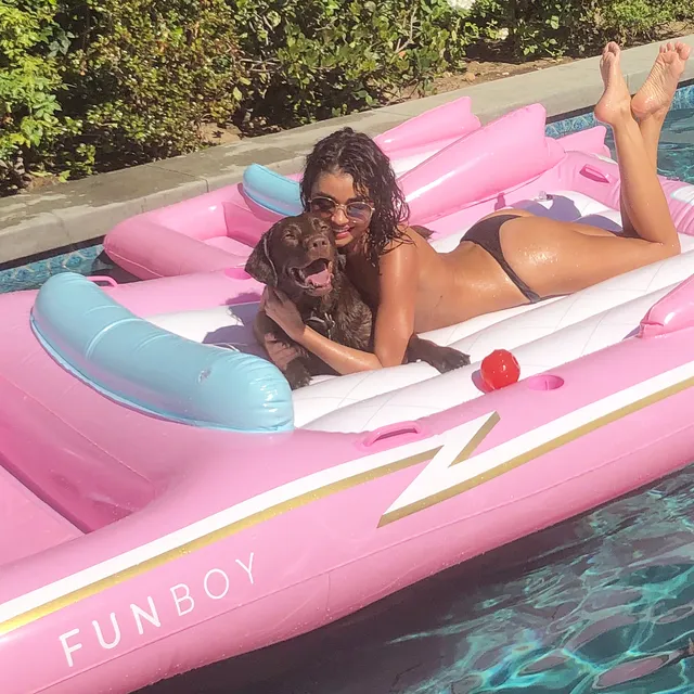 Sarah Hyland reclining on a pool float with a dog.