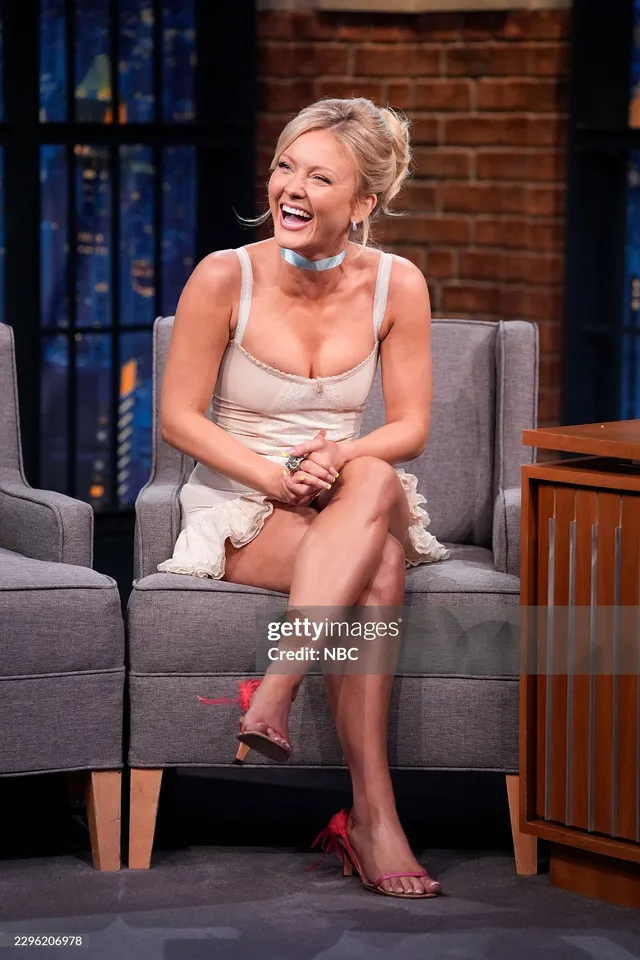 Zara Larsson sitting on a talk-show set in pink heels.