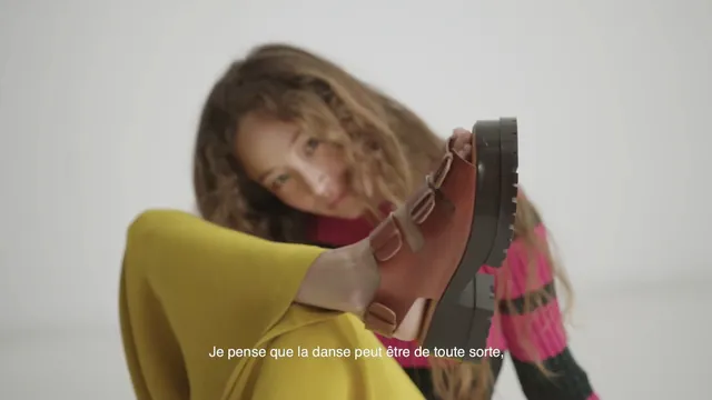 Havana Rose Liu raising a brown platform sandal toward the camera.