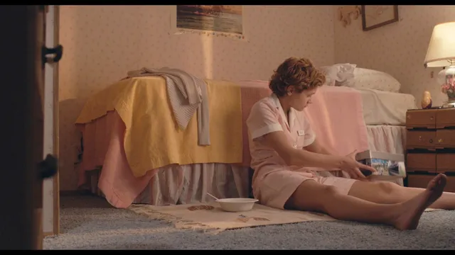 Olivia Cooke sitting on a floor with one leg extended.