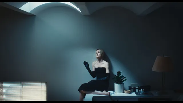 Sarah Pidgeon appearing in a dimly lit room in a black dress.