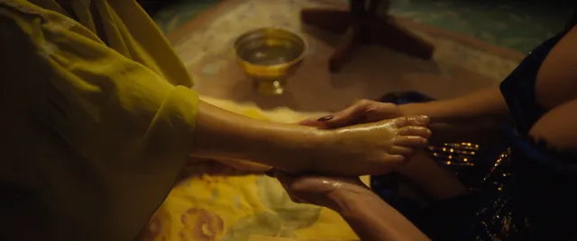 Melissa Barrera having her bare feet held over a towel in a film scene.