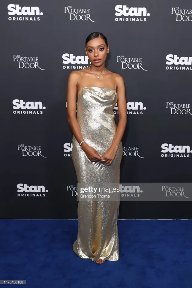 Sophie Wilde standing in a long silver gown at a premiere.