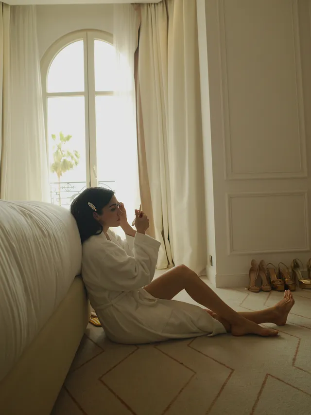 Hande Erçel sitting barefoot on the floor in a bathrobe.