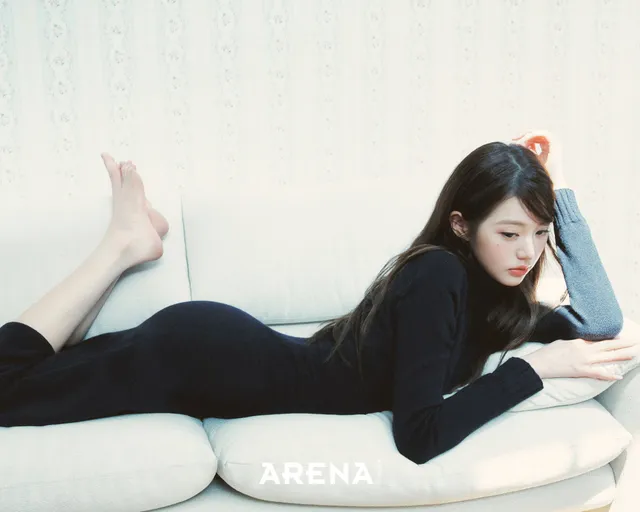 Jang Wonyoung lying on a pale sofa with bare feet raised.