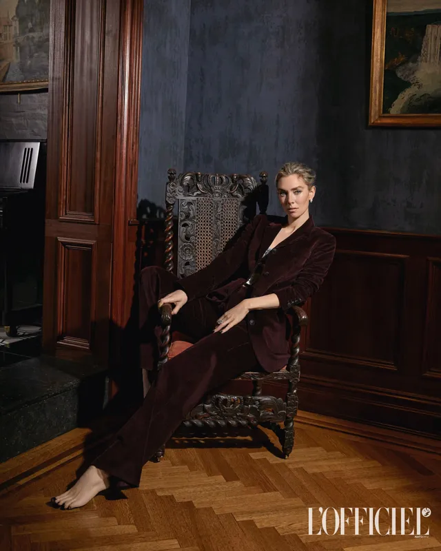 Vanessa Kirby seated in an ornate chair in a dark trouser suit.