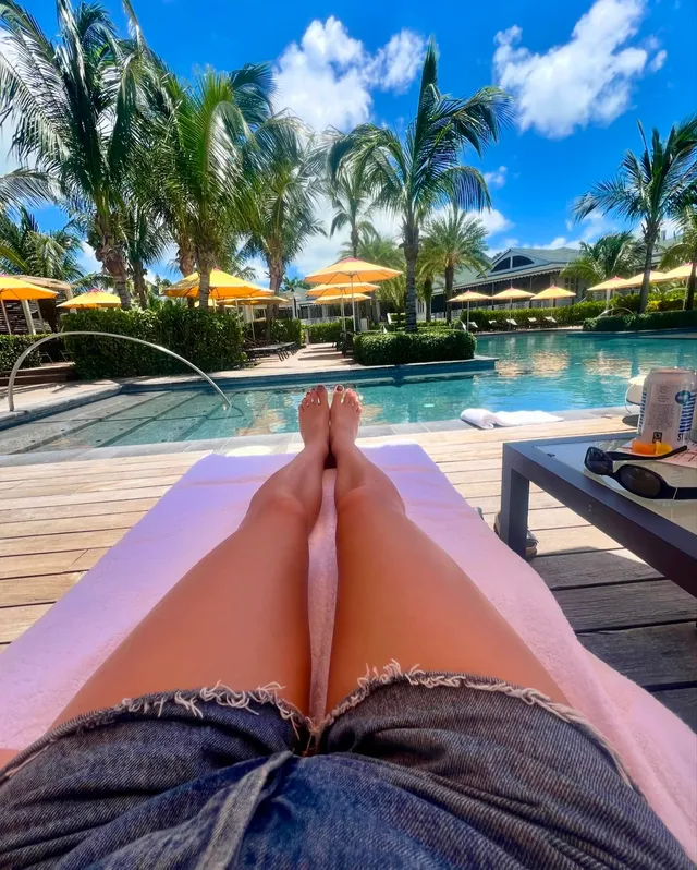 Daisy Edgar-Jones relaxing beside a sunny swimming pool.