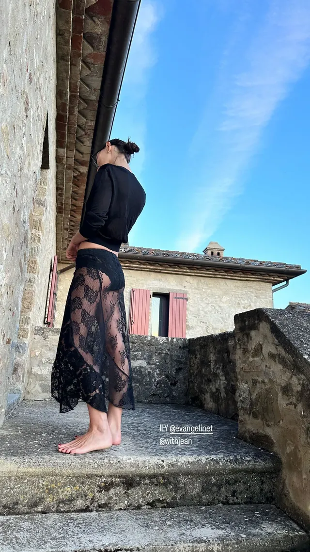 Phoebe Tonkin standing beside stone steps in a dark outfit.