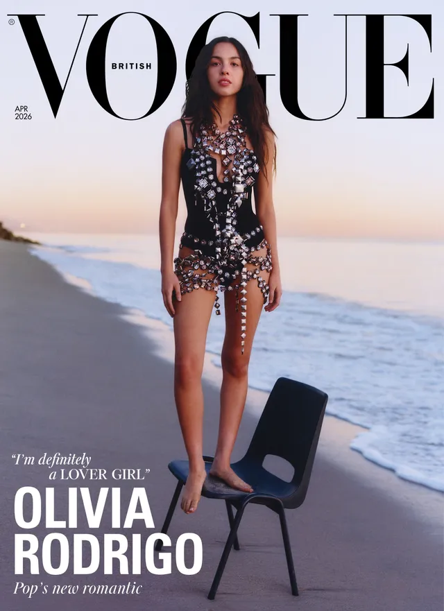 Olivia Rodrigo standing on a chair beside a beach.