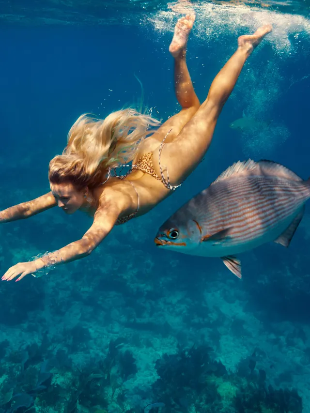 Zara Larsson swimming underwater with bare soles visible.