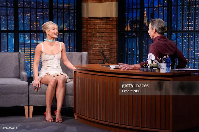 Zara Larsson sitting on a talk-show set in pink heels.