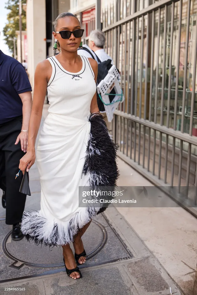 Sophie Wilde walking outside in a white dress and black heels.