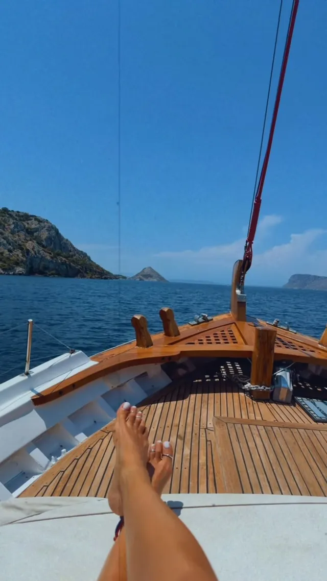 Rita Ora extending a bare foot toward the bow of a sailing boat.
