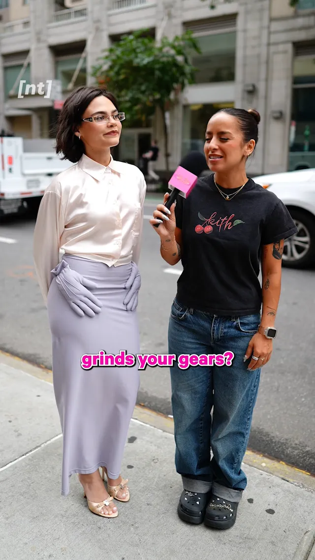 Ariana Greenblatt walking beside another person in a pale outfit and metallic heels.