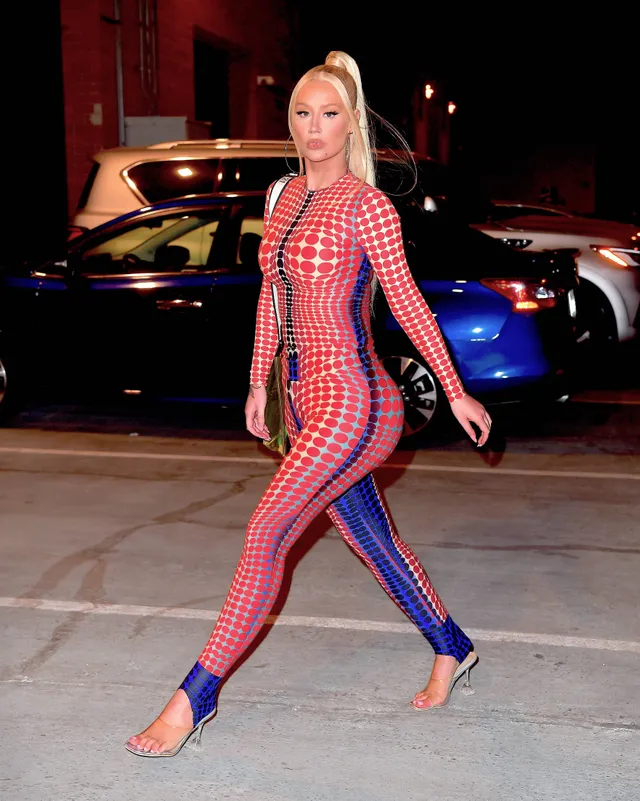 Iggy Azalea walking outdoors in a patterned outfit and clear heels.