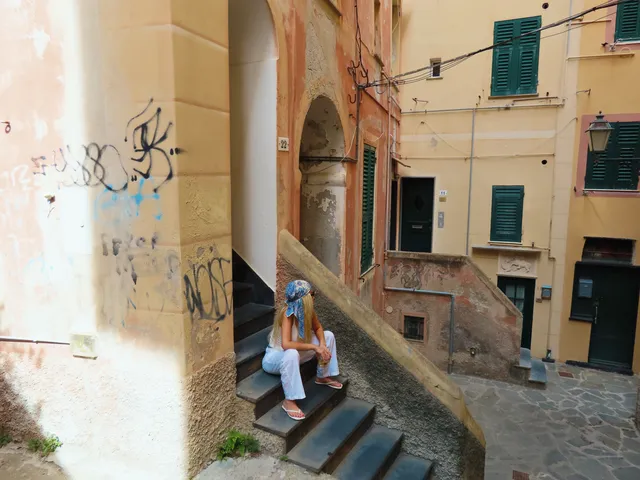 Christina Aguilera sitting on stone steps in a pale outfit.