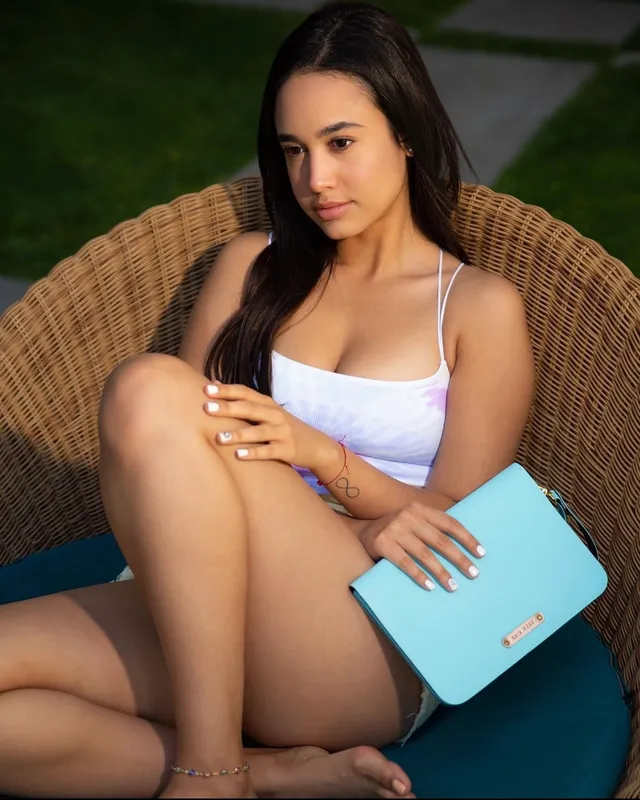 Emily Tosta sitting barefoot in a wicker chair.