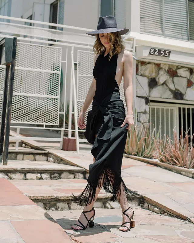 Adelaide Kane walking outdoors in a flowing black dress.