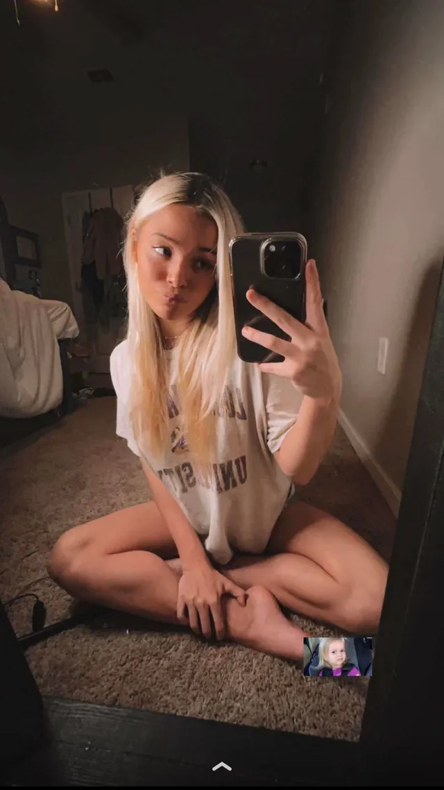 Olivia Dunne sitting cross-legged and taking a mirror selfie.