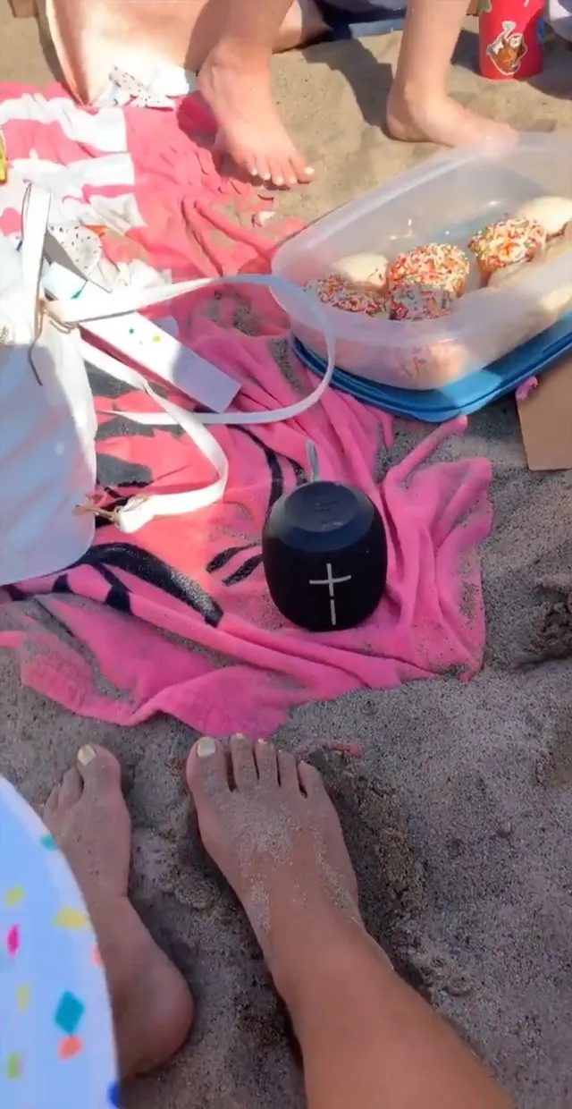 Isabela Merced resting a bare foot beside a picnic spread.