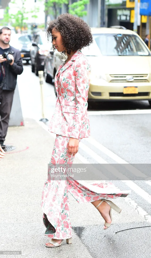 Samantha Logan walking outside in a floral trouser suit and pale heels.