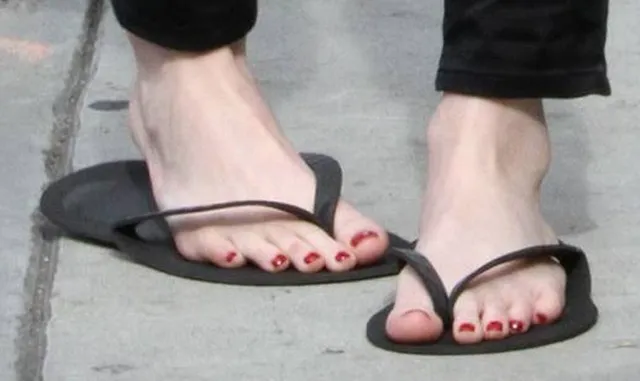 Emma Roberts wearing black flat sandals in a close detail.