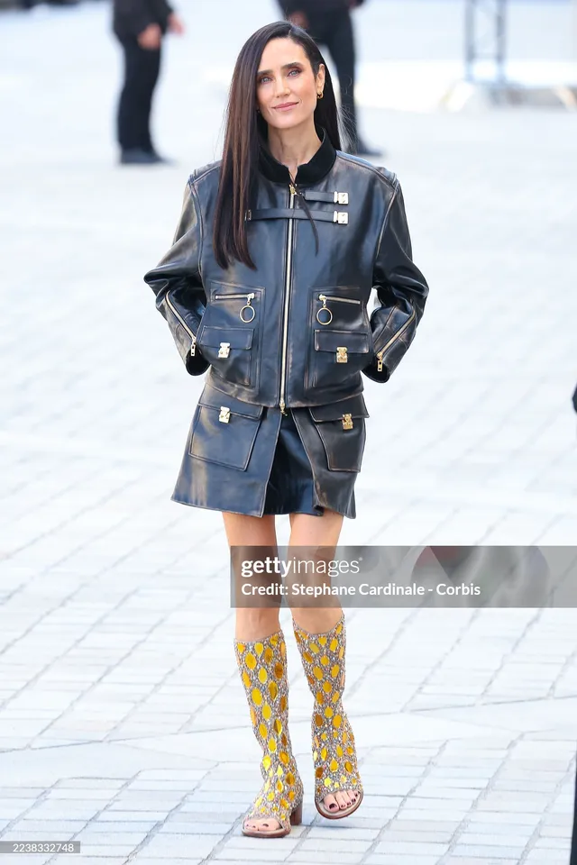Jennifer Connelly walking at a fashion event in patterned boots.