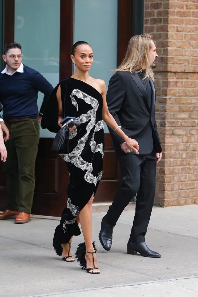 Zoe Saldaña walking out of a building in a patterned evening gown.