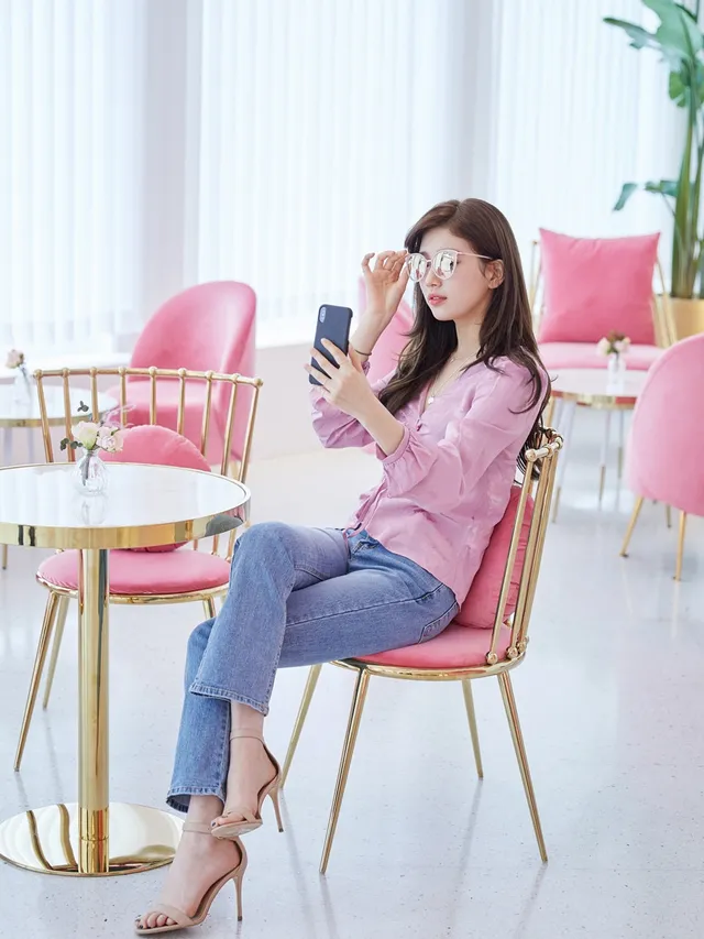 Bae Suzy sitting in jeans and pale heels for a mirror photograph.