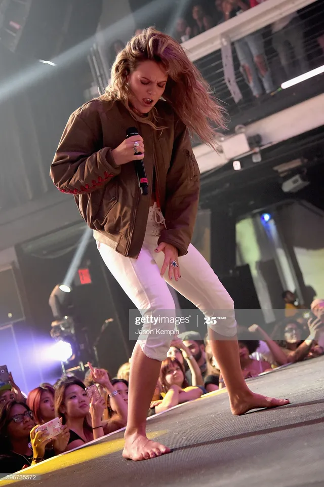 Tove Lo singing barefoot near the front of a stage.