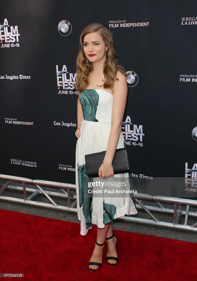 Willa Fitzgerald wearing black heels with a pale dress at a festival.