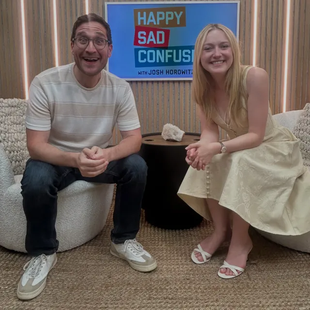 Dakota Fanning sitting with an interviewer in a pale outfit and sandals.