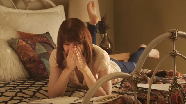 Bryce Dallas Howard lying on a bed during a screen scene.