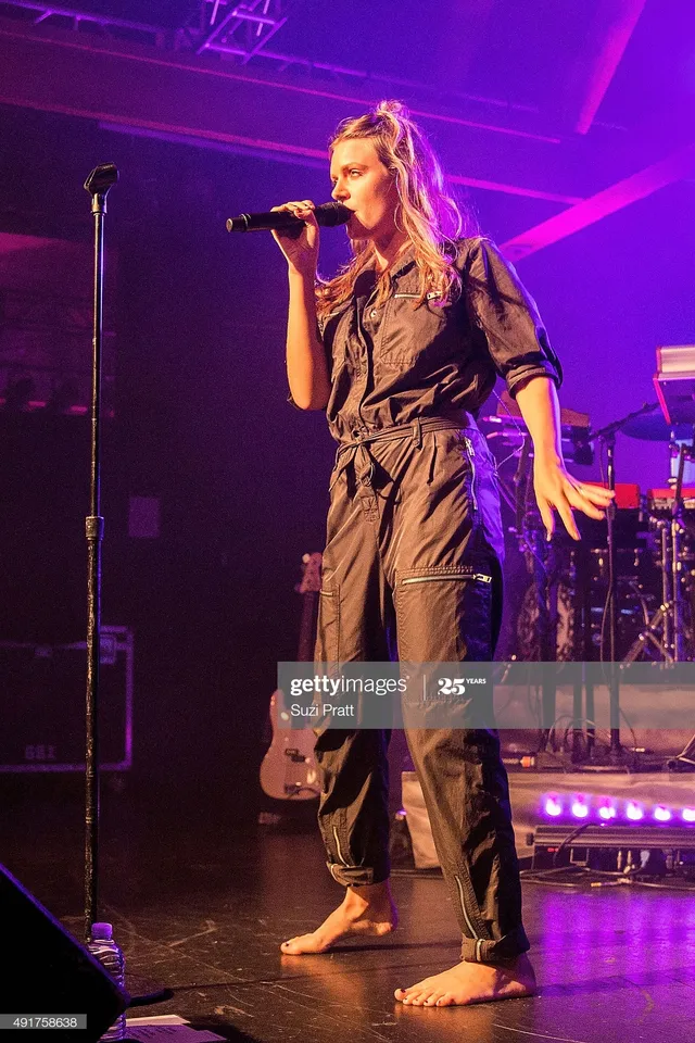 Tove Lo singing barefoot on stage in a dark outfit.