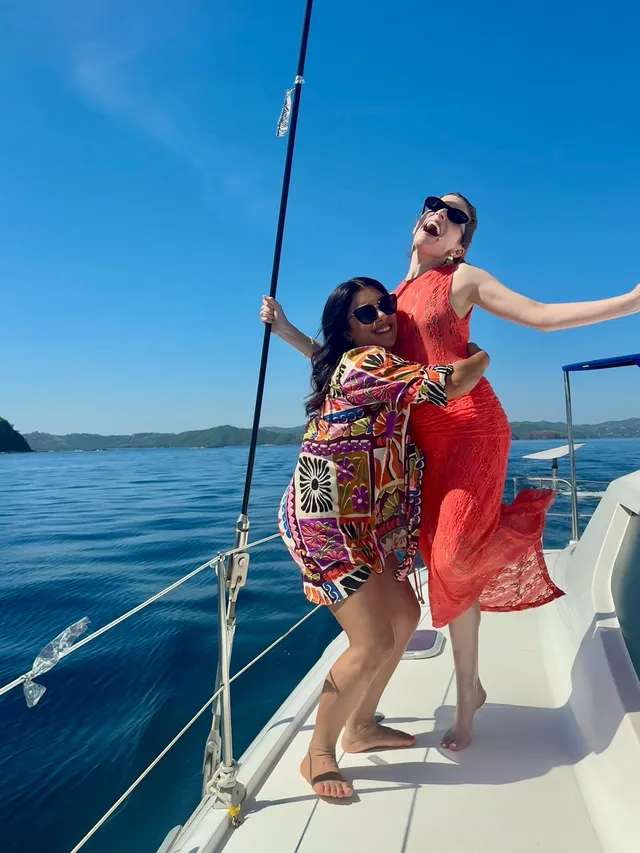 Anna Kendrick standing barefoot with a friend on a sailing boat.