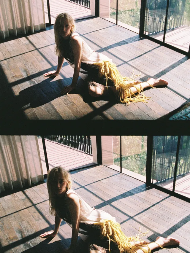 Maika Monroe posing barefoot on a sunlit wooden floor.