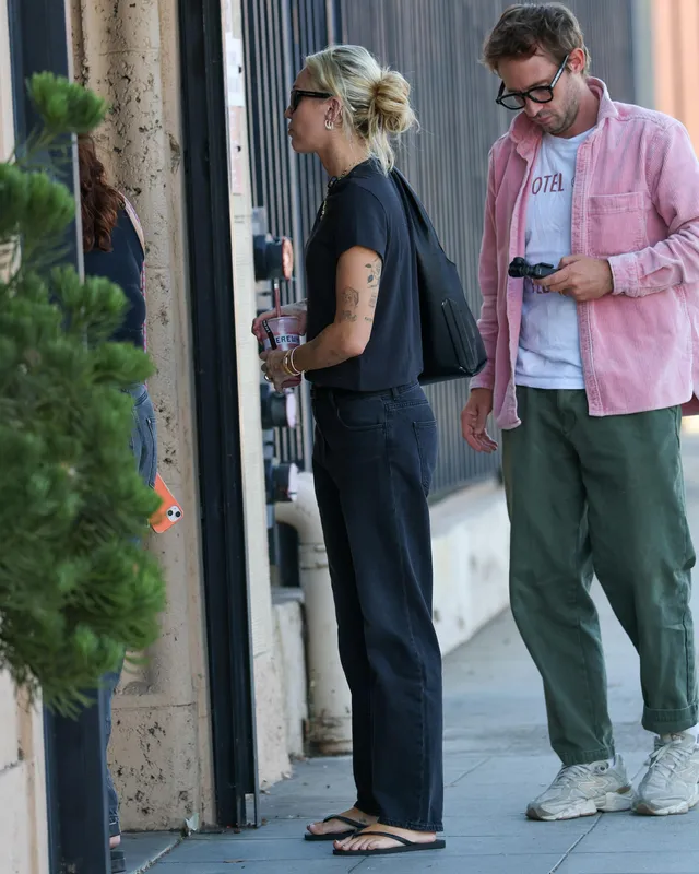 Miley Cyrus walking outside in jeans and flip-flops.