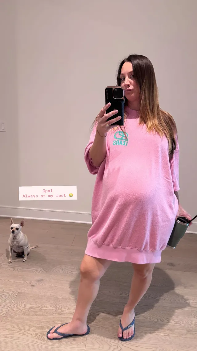 Kaley Cuoco posing for a mirror photograph in a pink dress and flip-flops.