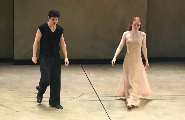 Sadie Sink walking barefoot beside another performer onstage.