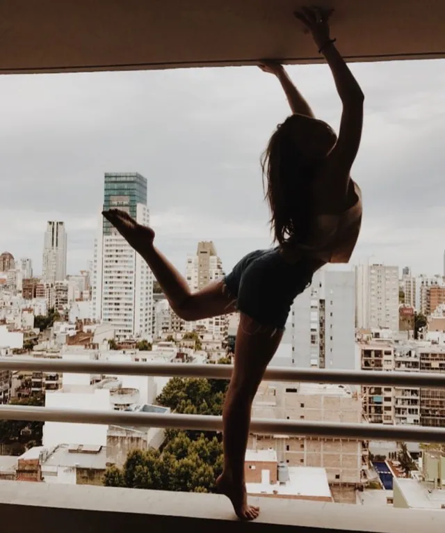 Danielle Campbell posing on a balcony overlooking city buildings.