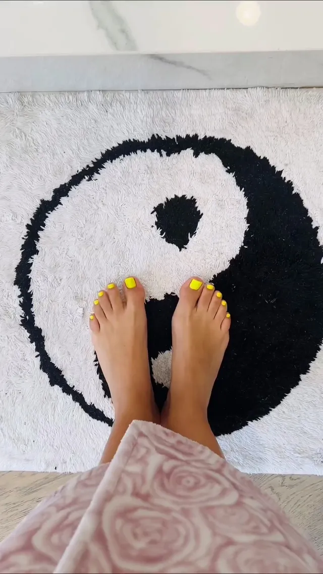 Victoria Justice standing barefoot on a patterned black and white mat.