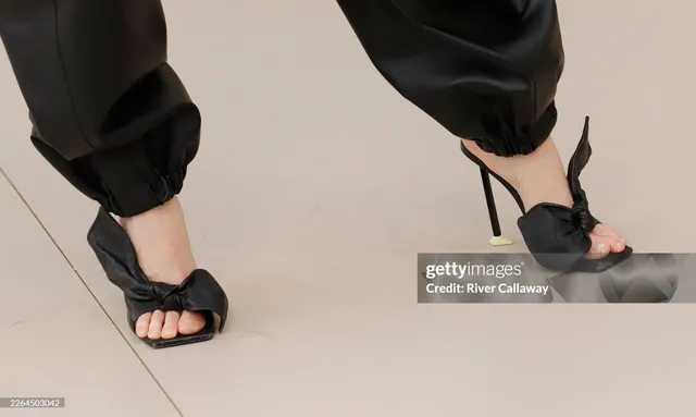Elizabeth Olsen wearing black bow-front heels with black trousers.