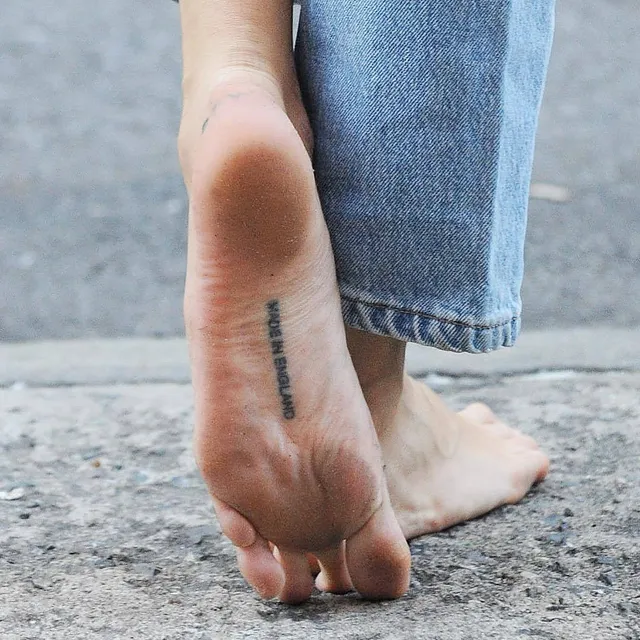 Cara Delevingne standing on tiptoe in jeans.