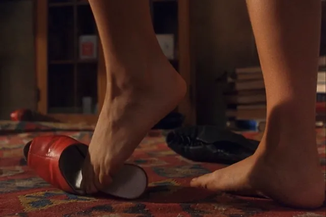 Salma Hayek a close detail of a bare foot beside a red high heel.