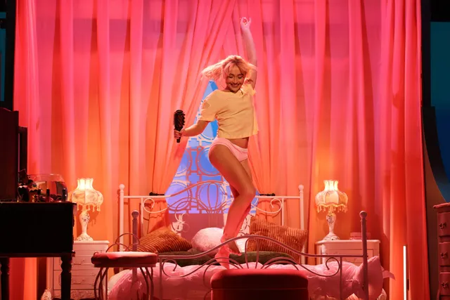 Sabrina Carpenter performing onstage in a pale outfit and heels.