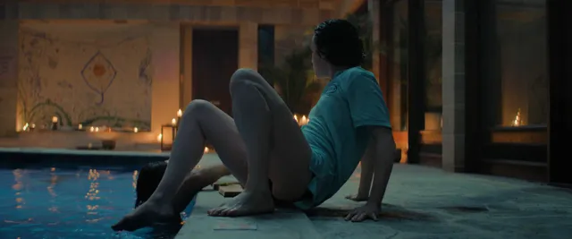 Daisy Ridley resting beside an indoor pool in a screen scene.