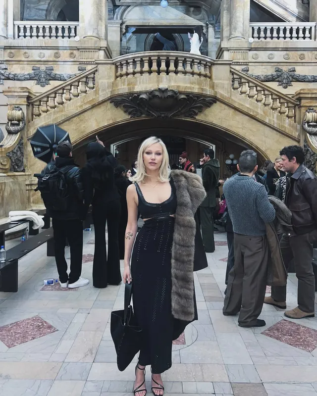 Grace VanderWaal posing outdoors in a black dress and heels.